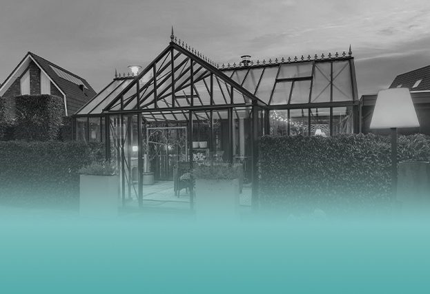 Moderne glazen tuinkamer met warme verlichting en terras in de avond