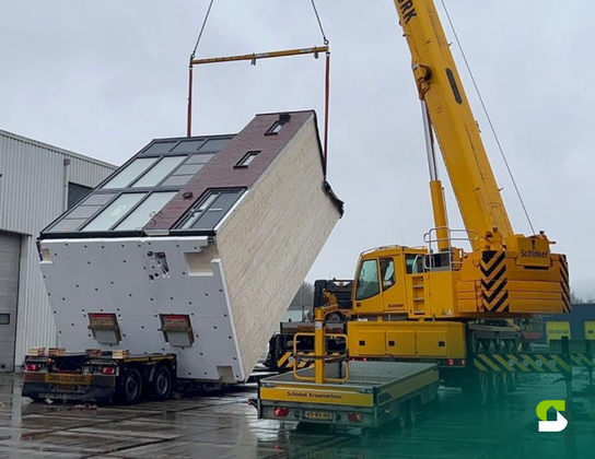 Prefab Starblock-woning wordt met een hijskraan op een dieplader getild